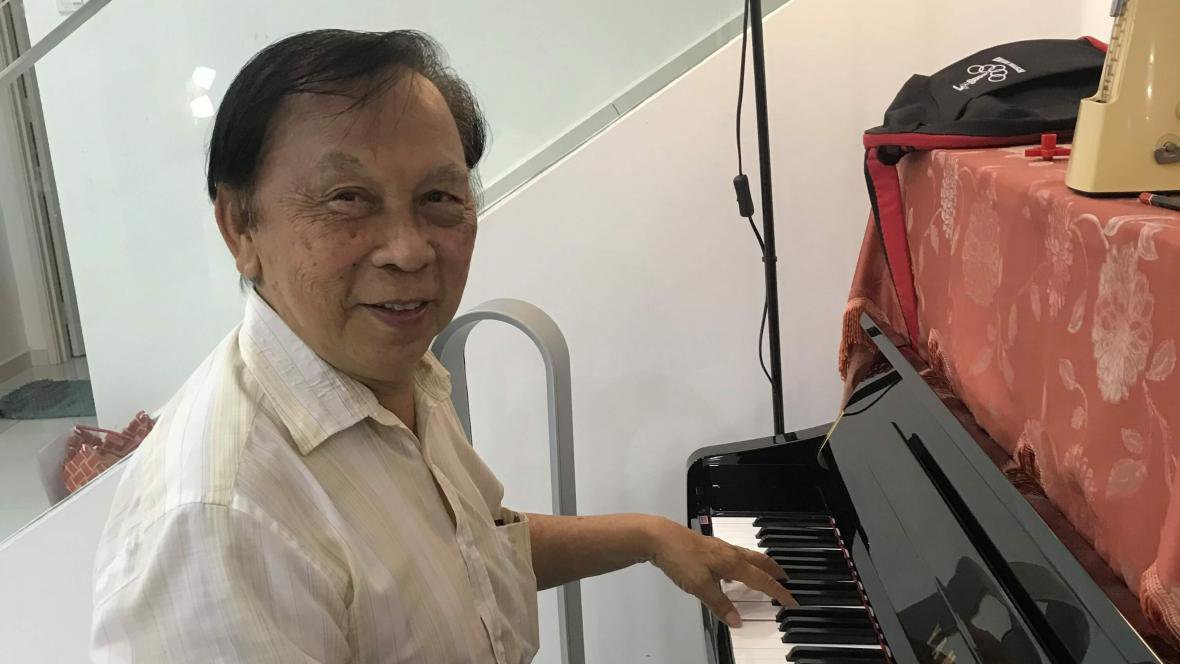 Hock Chye playing the piano, smiling into the camera.