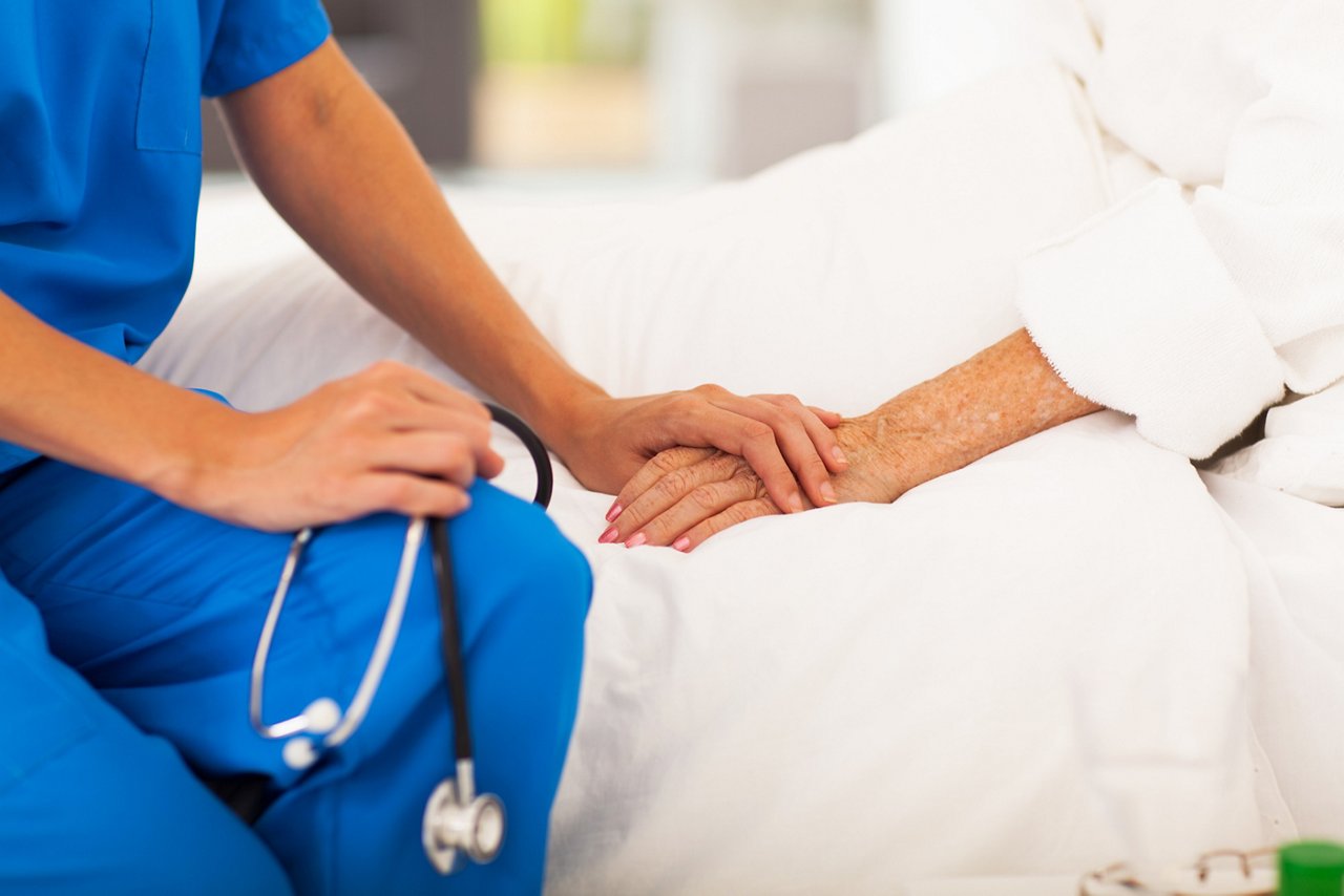 medical doctor holding senior patient's hands and comforting her