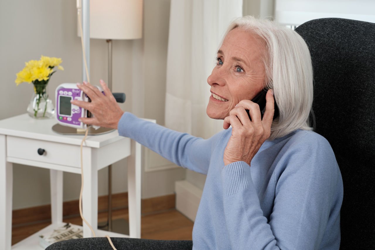 Kvinne som snakker i telefon med amika+ ernæringspumpe