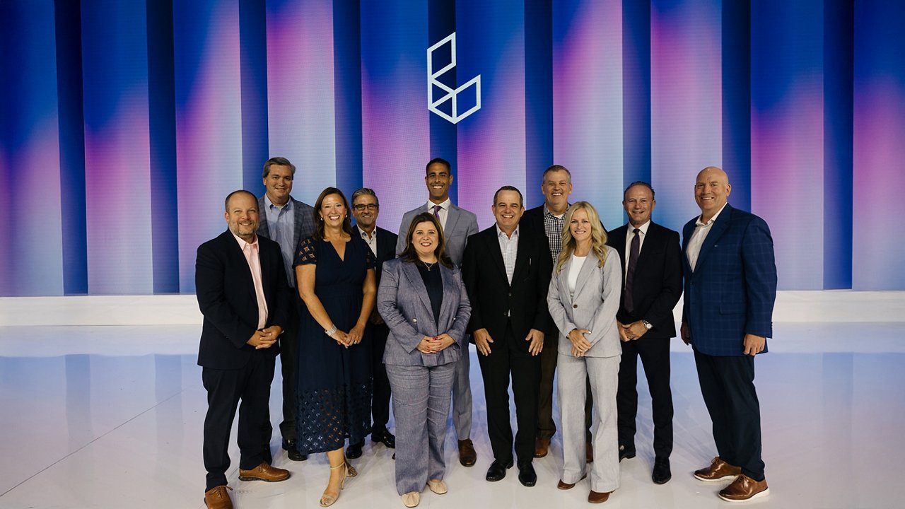Group of ten Premier Legacy Award winners in formal attire, standing in two rows against a blue and purple striped background with a geometric logo.