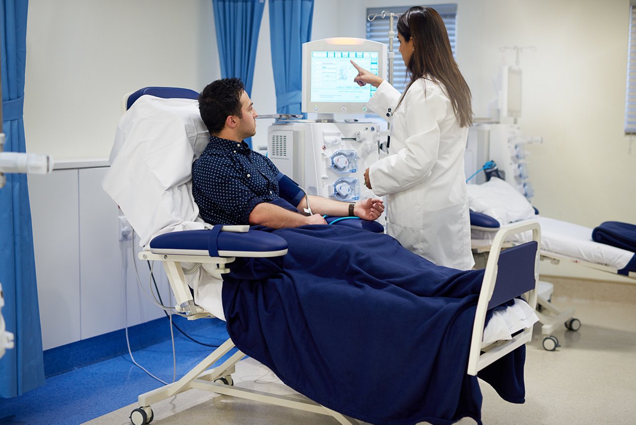 Man, doctor and dialysis machine in hospital for kidney assessment, organ fail and medical diagnosis for health. Patient, woman and screen exam for Nephrology, filter blood and hemodialysis treatment.