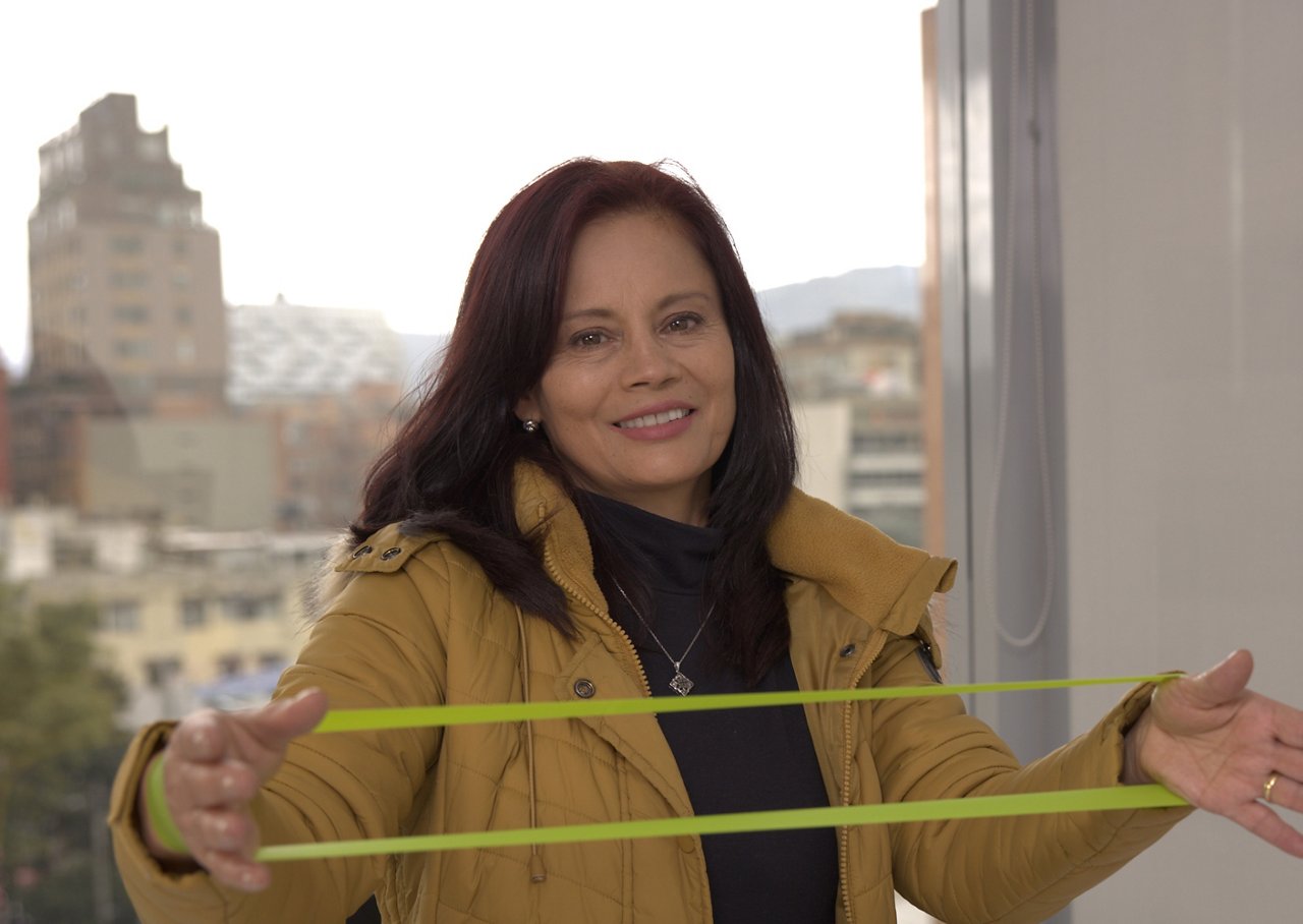 Diana is stretching a resistance band in front of a window.