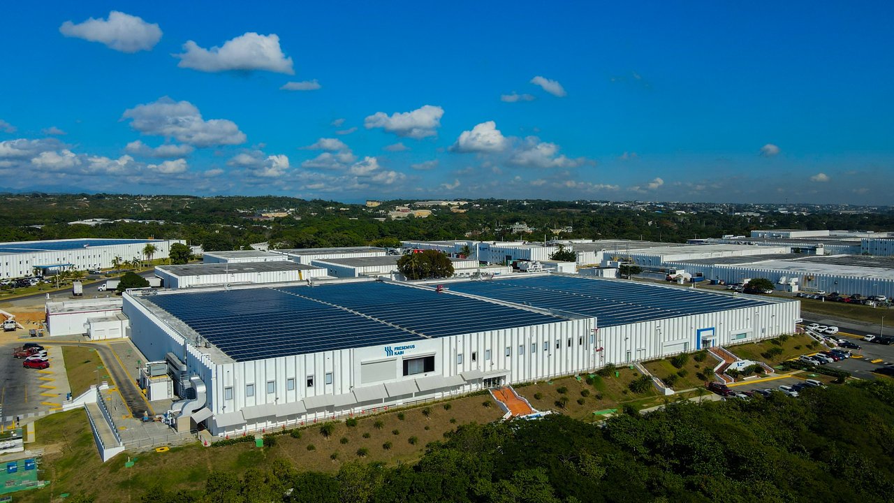 Aerial view of the Haina plant of Fresenius Kabi with solar panels on the roof and a blue sky.