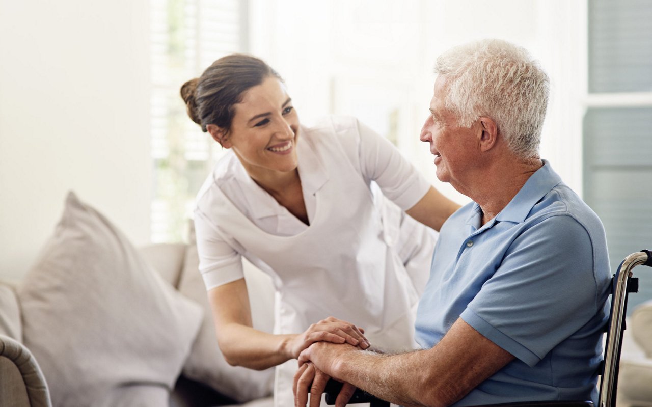 Shot of a caregiver helping a senior man in a wheelchair at home