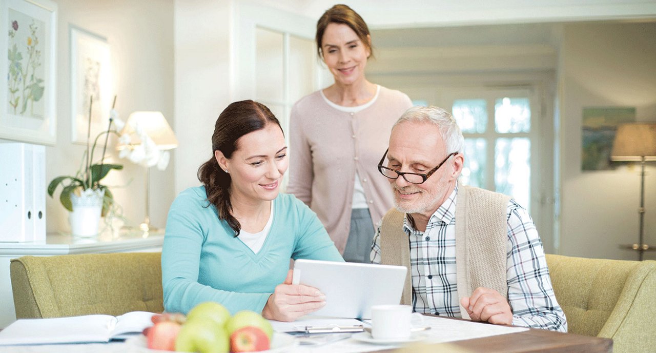 Familie am TIsch sieht sich etwas am Tablet an
