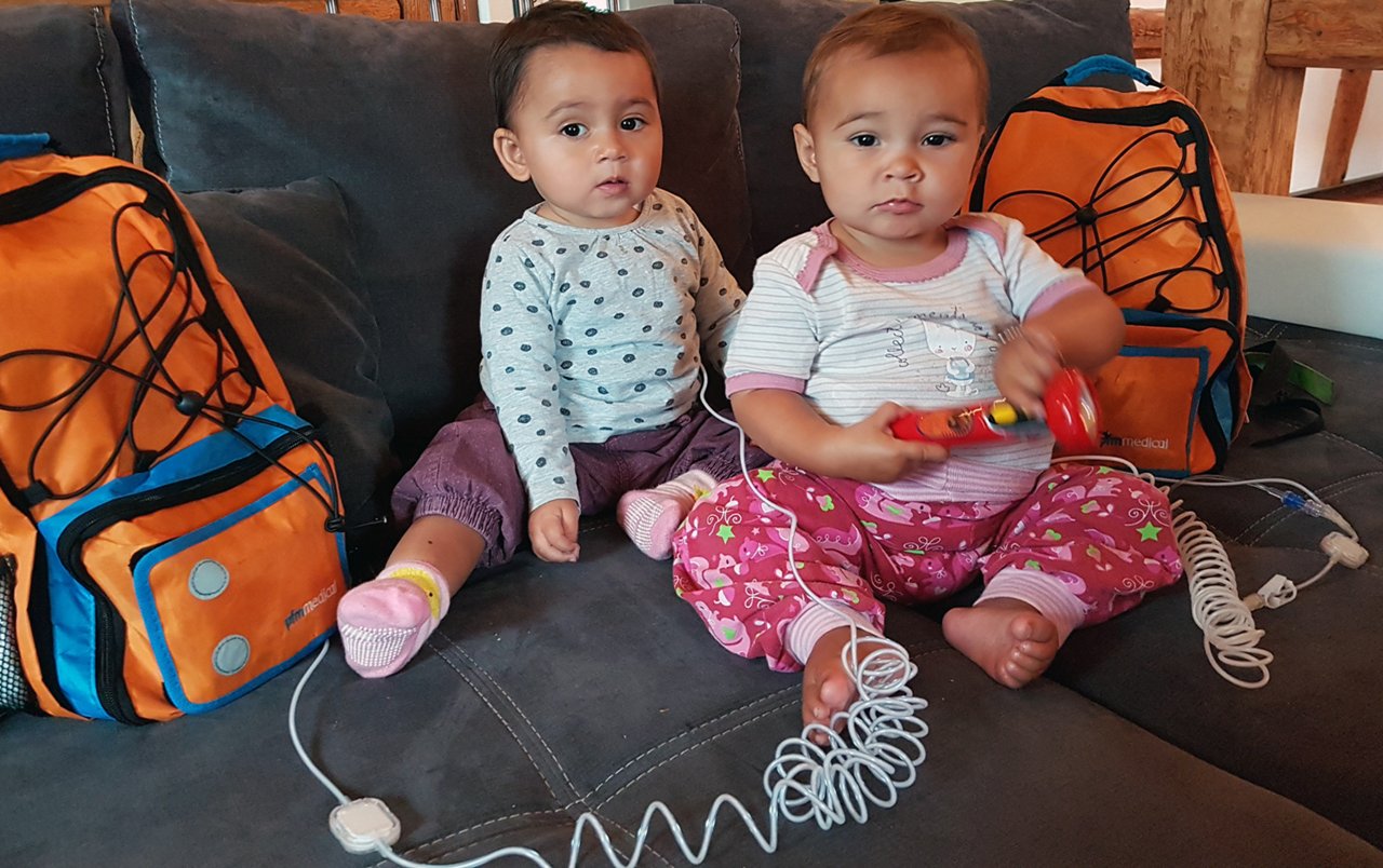 Ana and Emma with their colorful backpacks that allow for great mobility during the parenteral nutrition process.