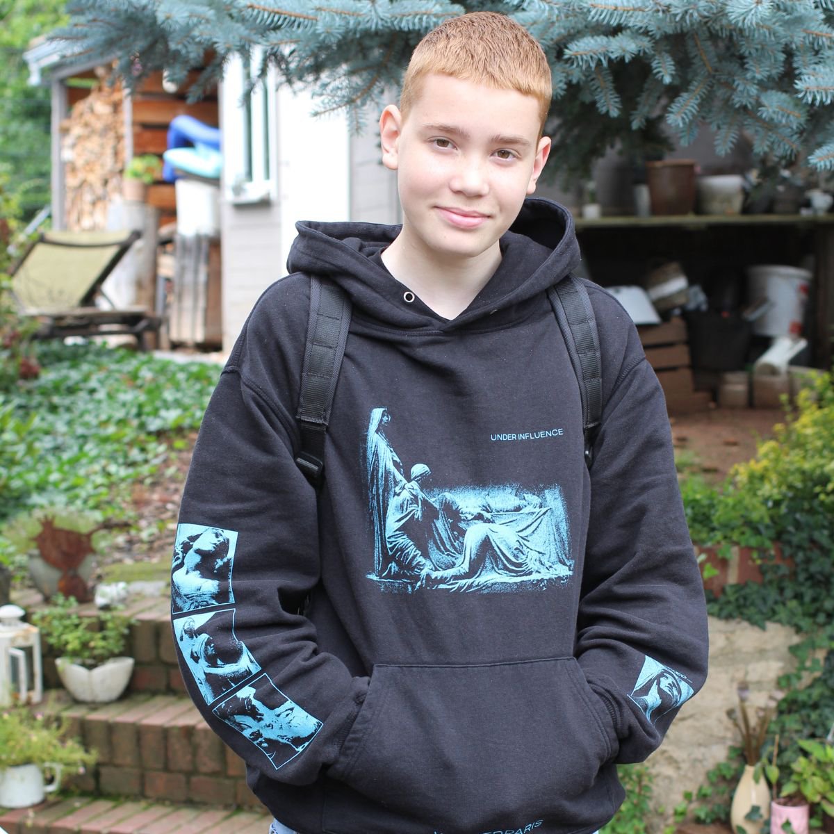 Junge mit Rucksack steht vor seinem Haus