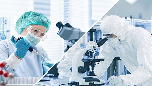 Two scientists in protective gear working with microscopes in a laboratory setting.