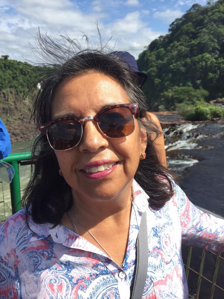 Nancy smiling into the camera, standing on a viewpoint above waterfalls.