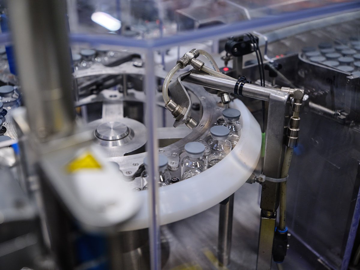 Close-up of an automated manufacturing system handling pharmaceutical glass vials on a production conveyor.
