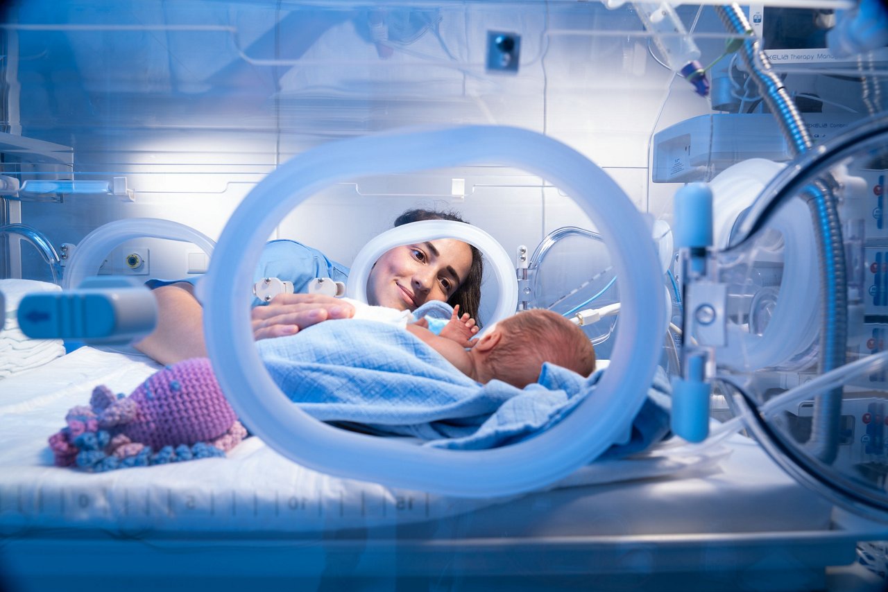 Nurse with preterm infant in an incubator
