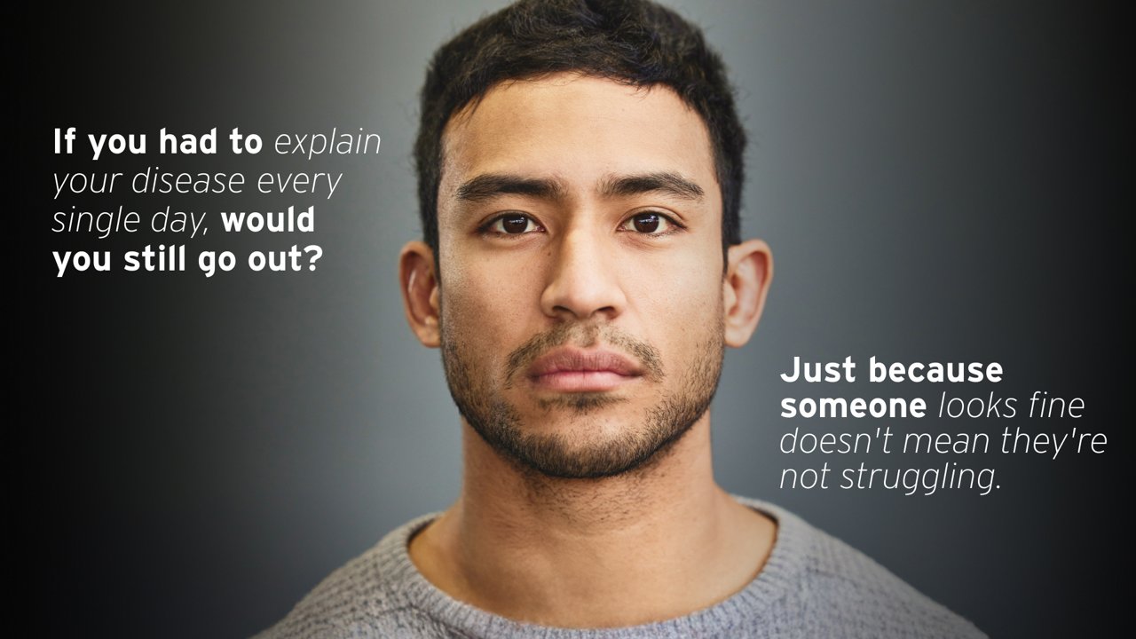 A serious-looking man with short dark hair, wearing a grey sweater, is centered in the image. On the left side, text reads: 'If you had to explain your disease every single day, would you still go out?' On the right side, it says: 'Just because someone looks fine doesn't mean they're not struggling.'