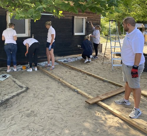 Die Mitarbeiterinnen und Mitarbeiter streichen die Gartenhütte