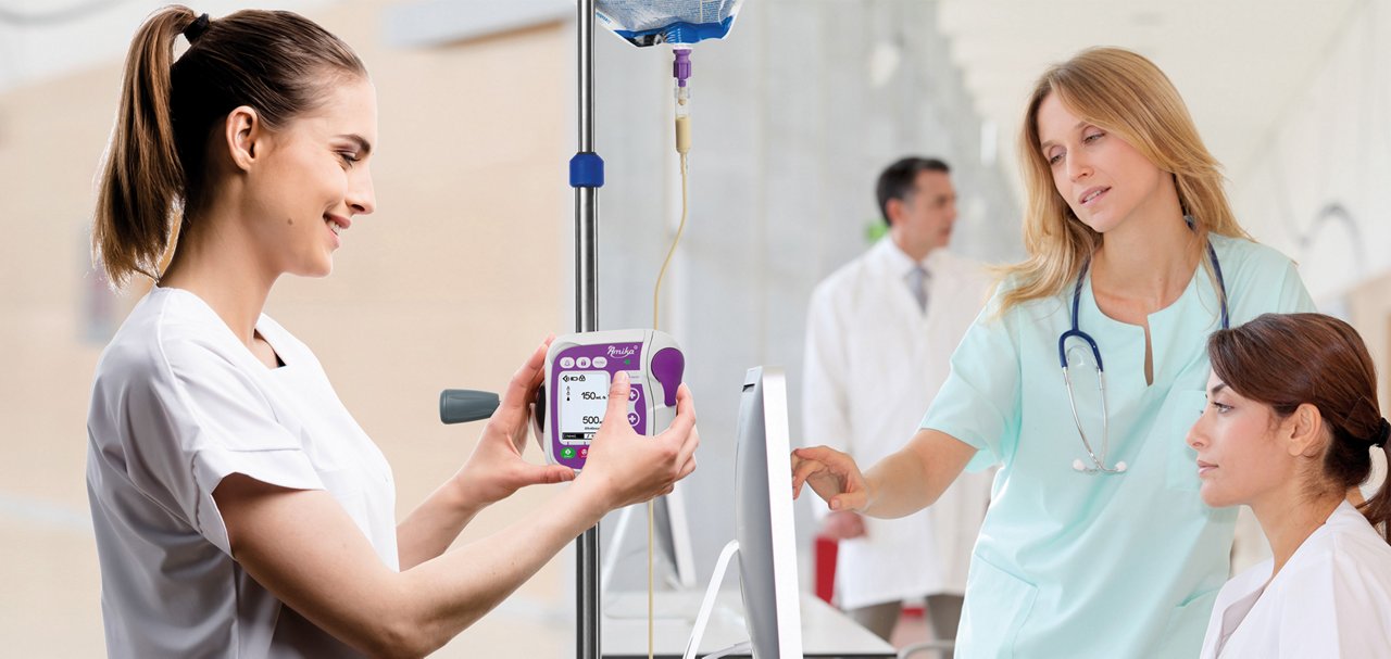 Healthcare professionals using an Amika+ infusion pump alongside a computer workstation in a clinical setting.