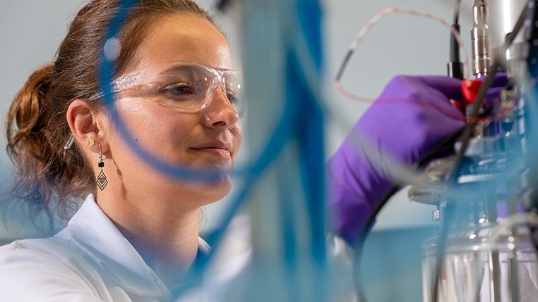 Person wearing purple gloves working with laboratory equipment.