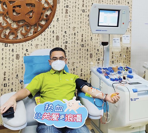 Person donating blood in a medical facility with a machine and tubes connected to the arm.