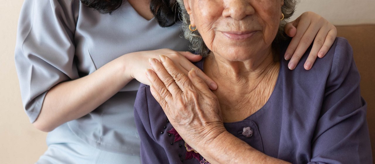 Friendly relationship between caregiver and happy eldery woman during nursing at home. Senior services and geriatric care concept.