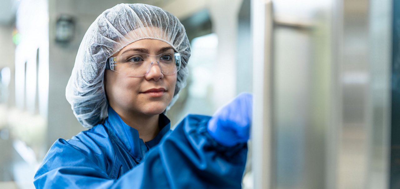Cleanroom technician wearing protective equipment operating manufacturing machinery