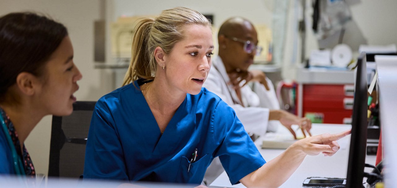 Two clinical staff members reviewing information together on a computer monitor at a workstation.