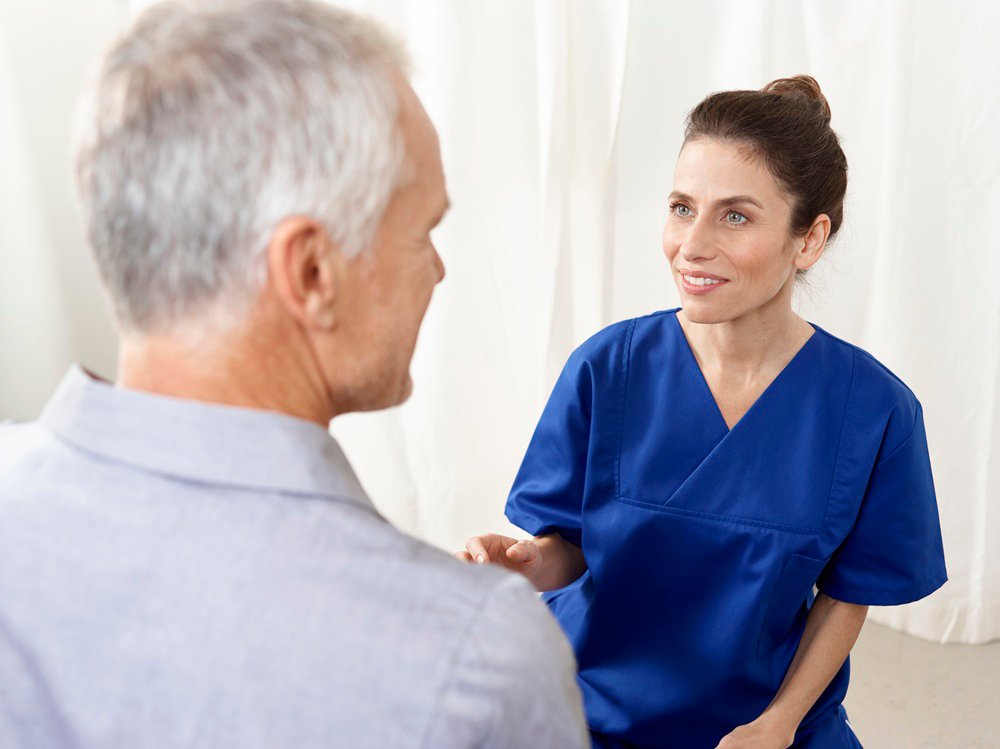 Eine Krankenpflegerin spricht mit einem Patienten