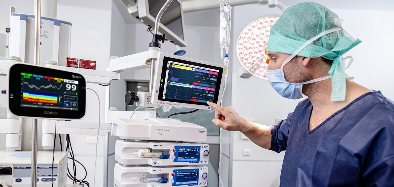 Clinician using a touchscreen infusion management system in an operating room.