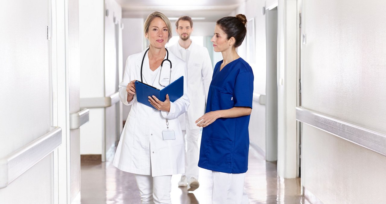 Ärztin und Pflegekraft besprechen sich auf einem Krankenhausflur