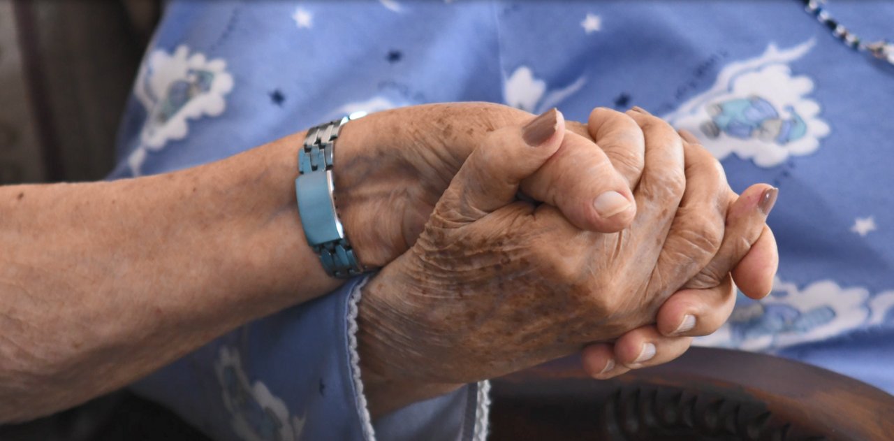 Picture of two elderly hands holding each other.