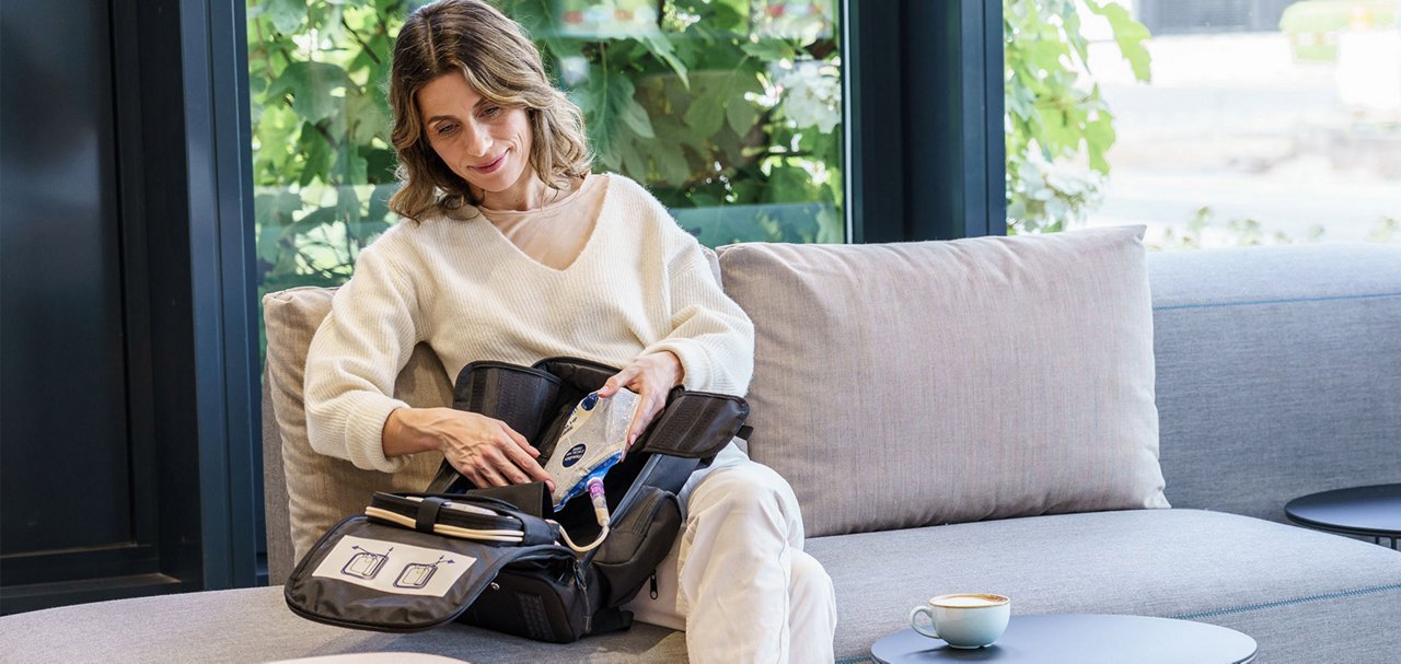 Person placing an enteral nutrition container into a portable backpack system in a home care environment.
