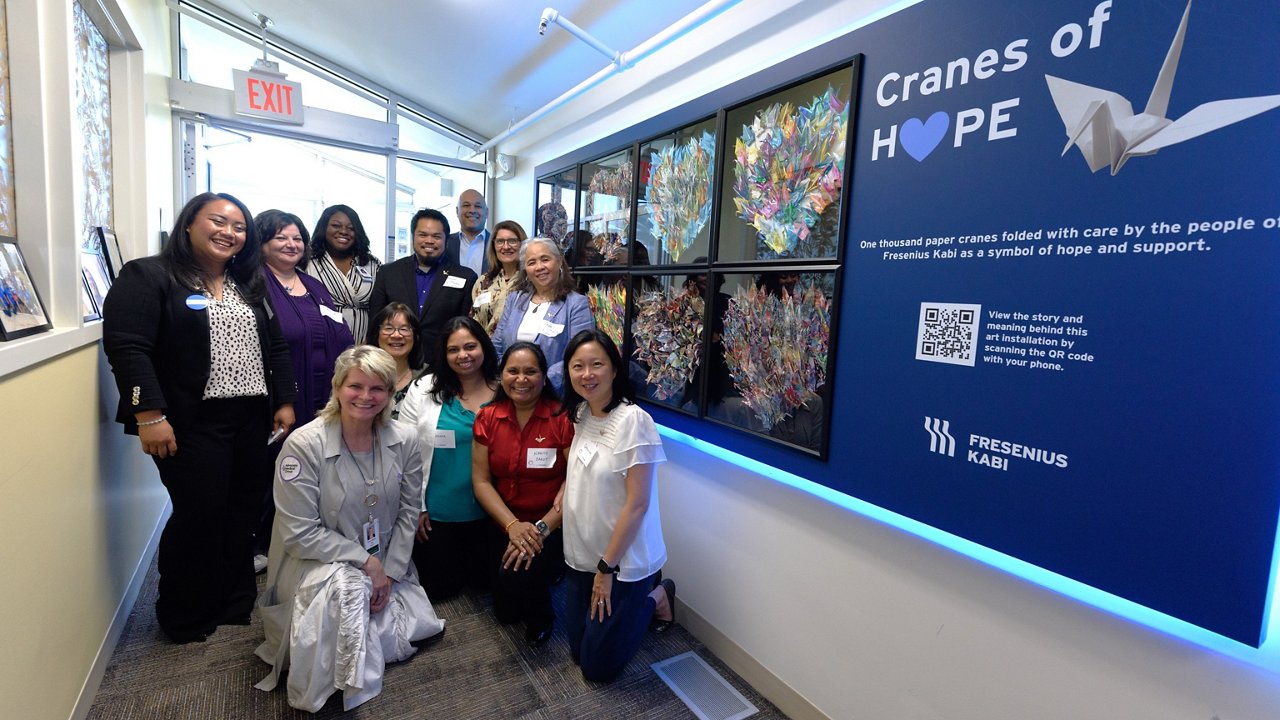 A group photo in front of a display of the paper crane artwork.