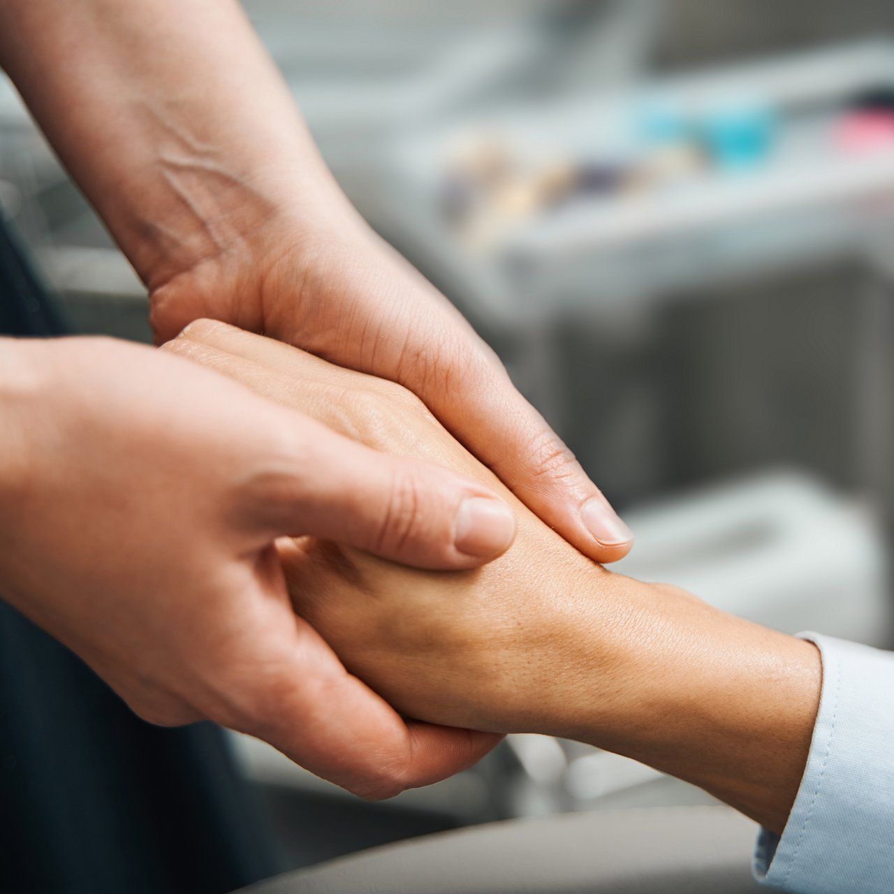 Close-up of two hands clasped in a comforting gesture.