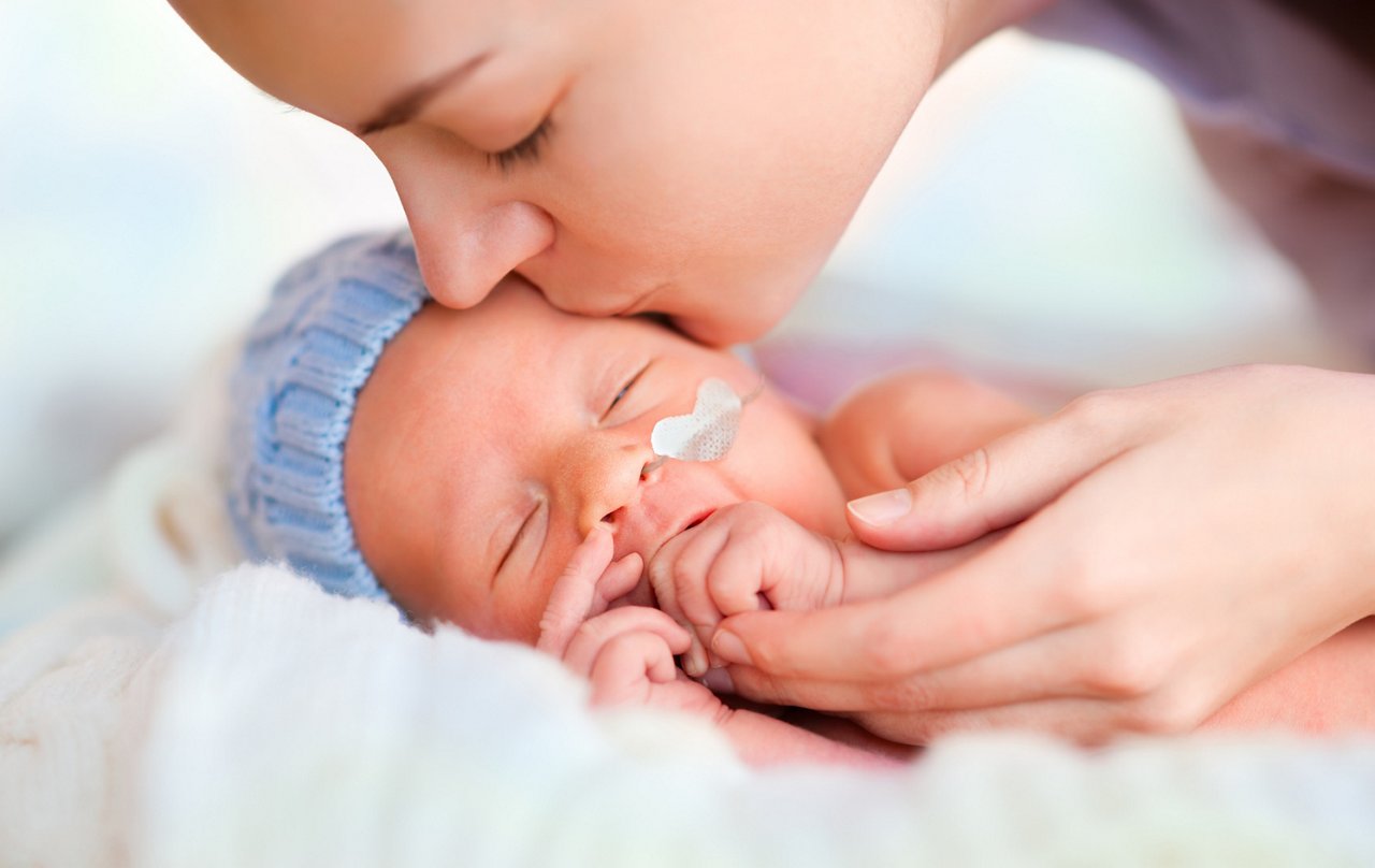 Close up of sleeping newborn and kissing mother