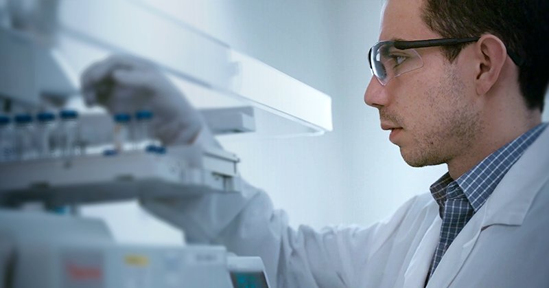 Scientist in lab coat and gloves working with lab equipment