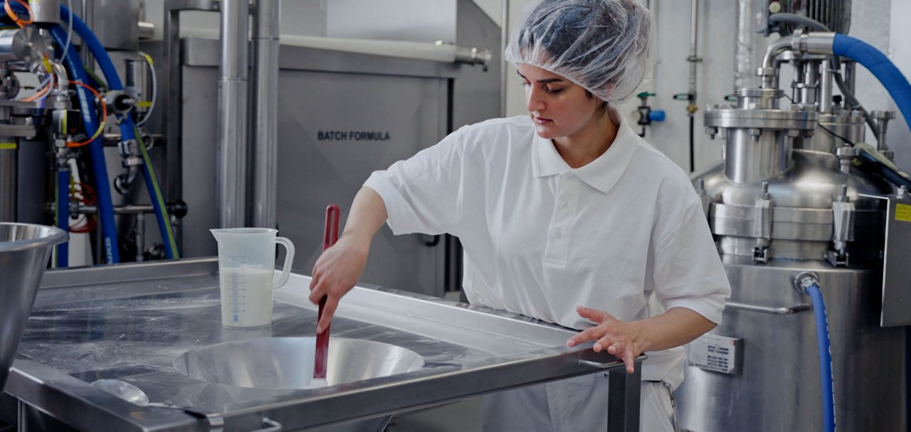 Personnel in a manufacturing facility handling ingredients and equipment used in nutrition product production.