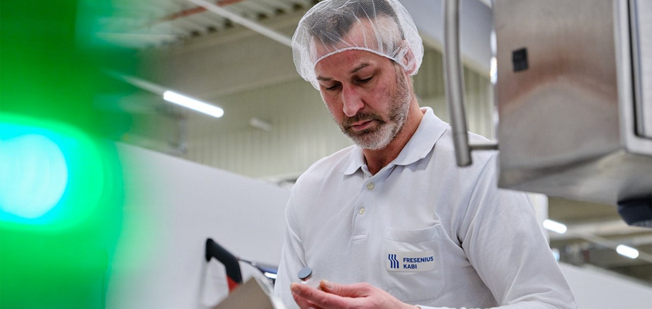 Manufacturing employee inspecting a pharmaceutical container in a production facility.