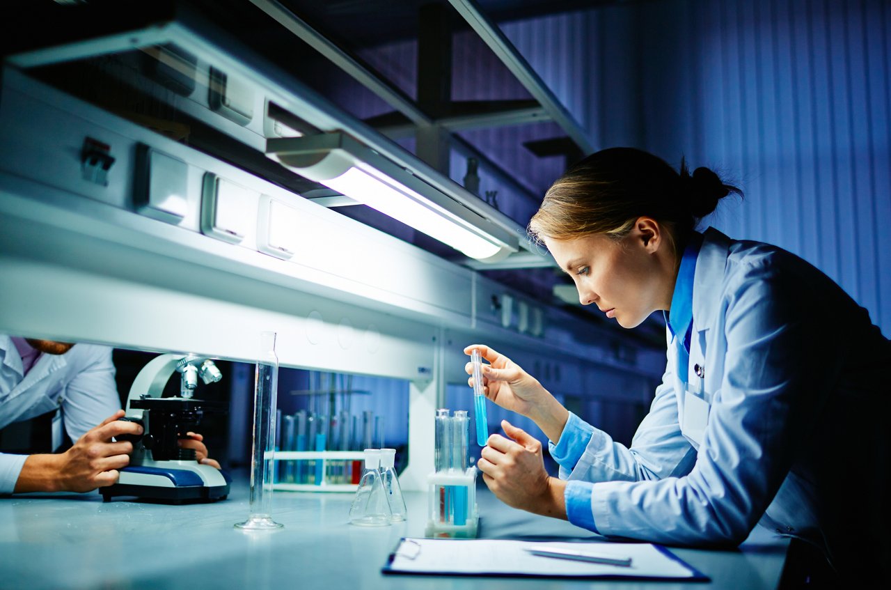 Young clinician looking at flask with liquid, Young clinician looking at flask with liquid