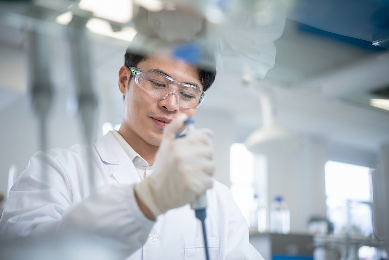 Scientist in a modern laboratory using a pipette for sample analysis in a pharmaceutical research setting